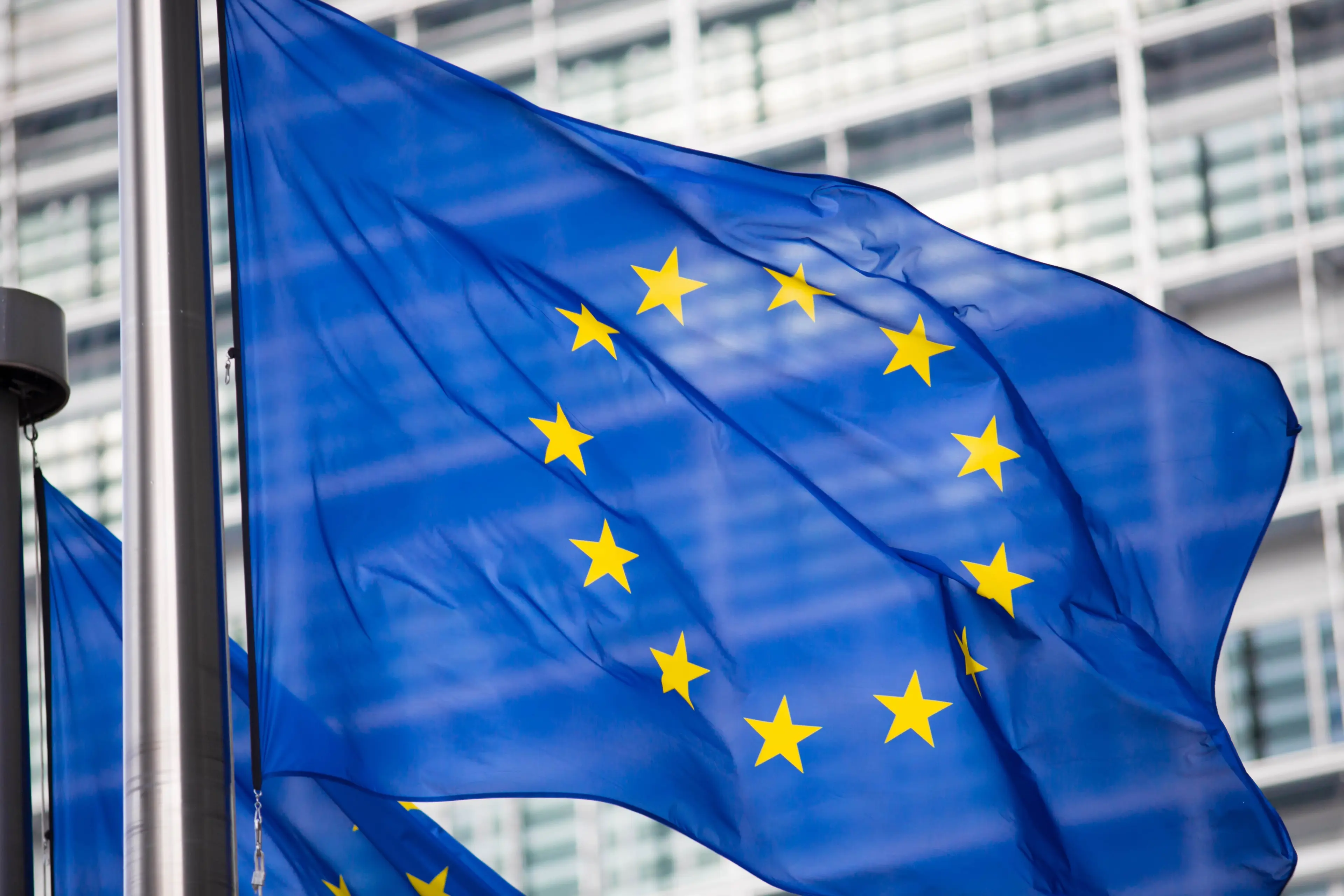 EU commission flag flying in front of the EU comm building