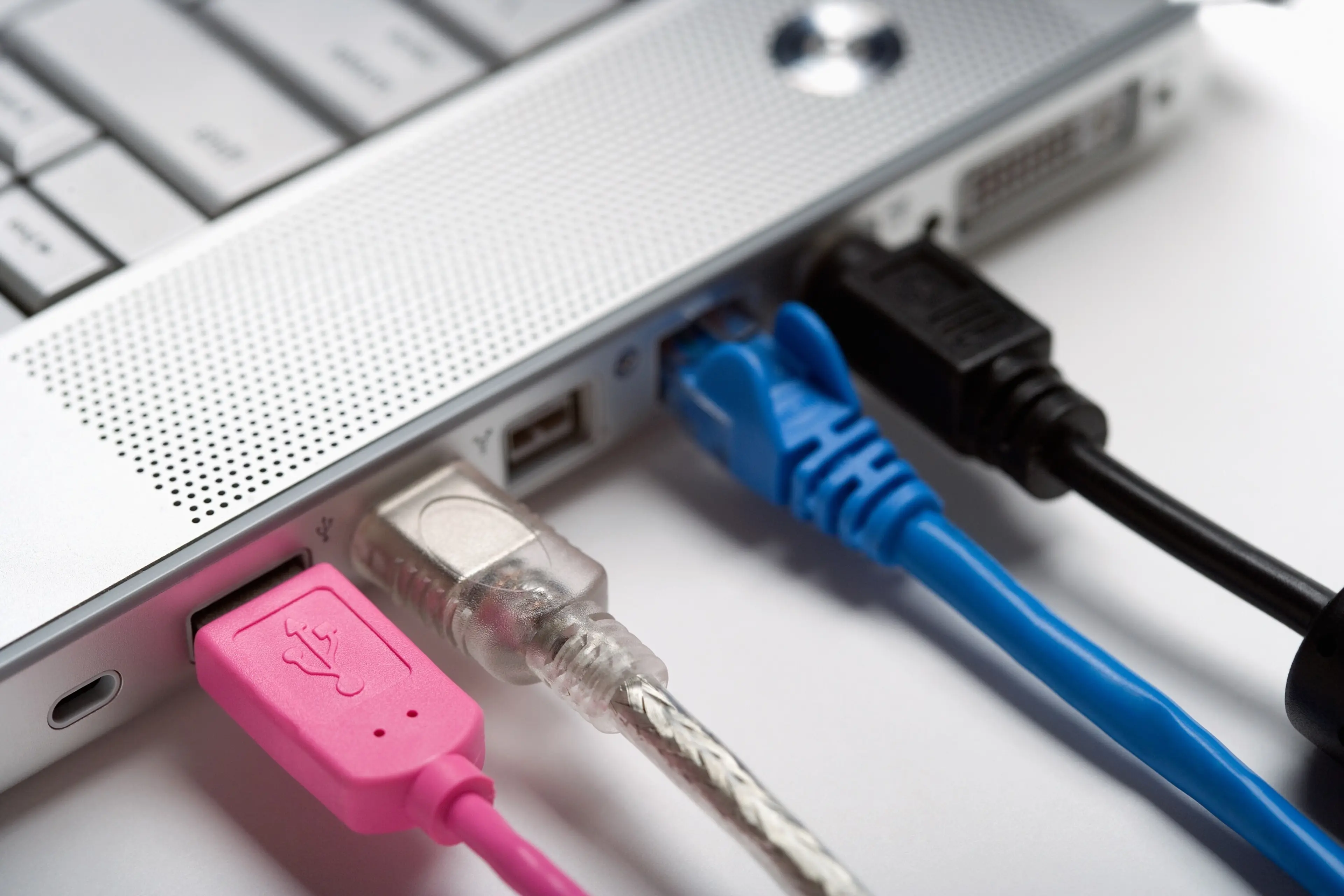 Laptop with pink, blue, black and white cables attached