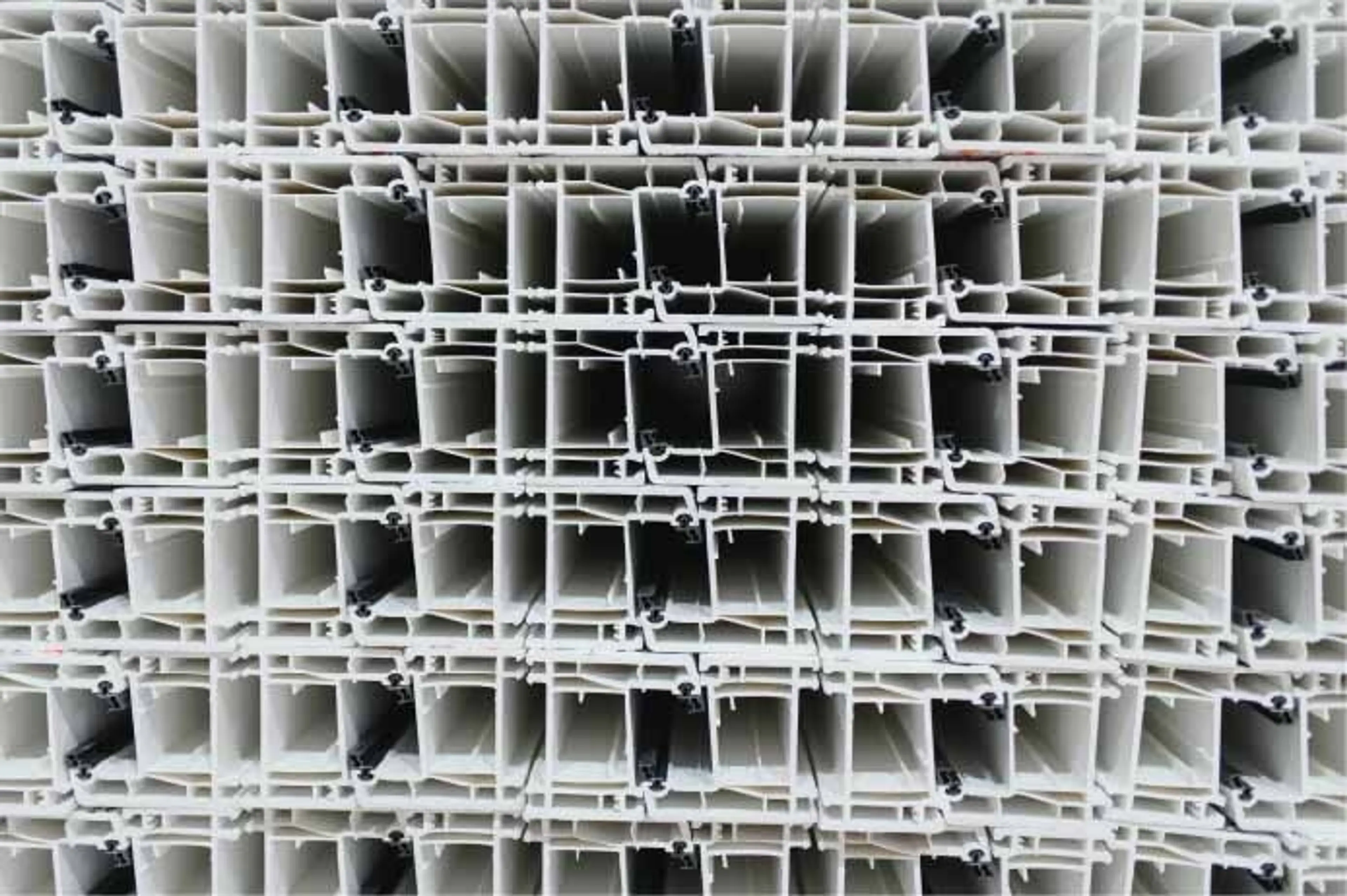 Many identical white pvc window frames are neatly stacked