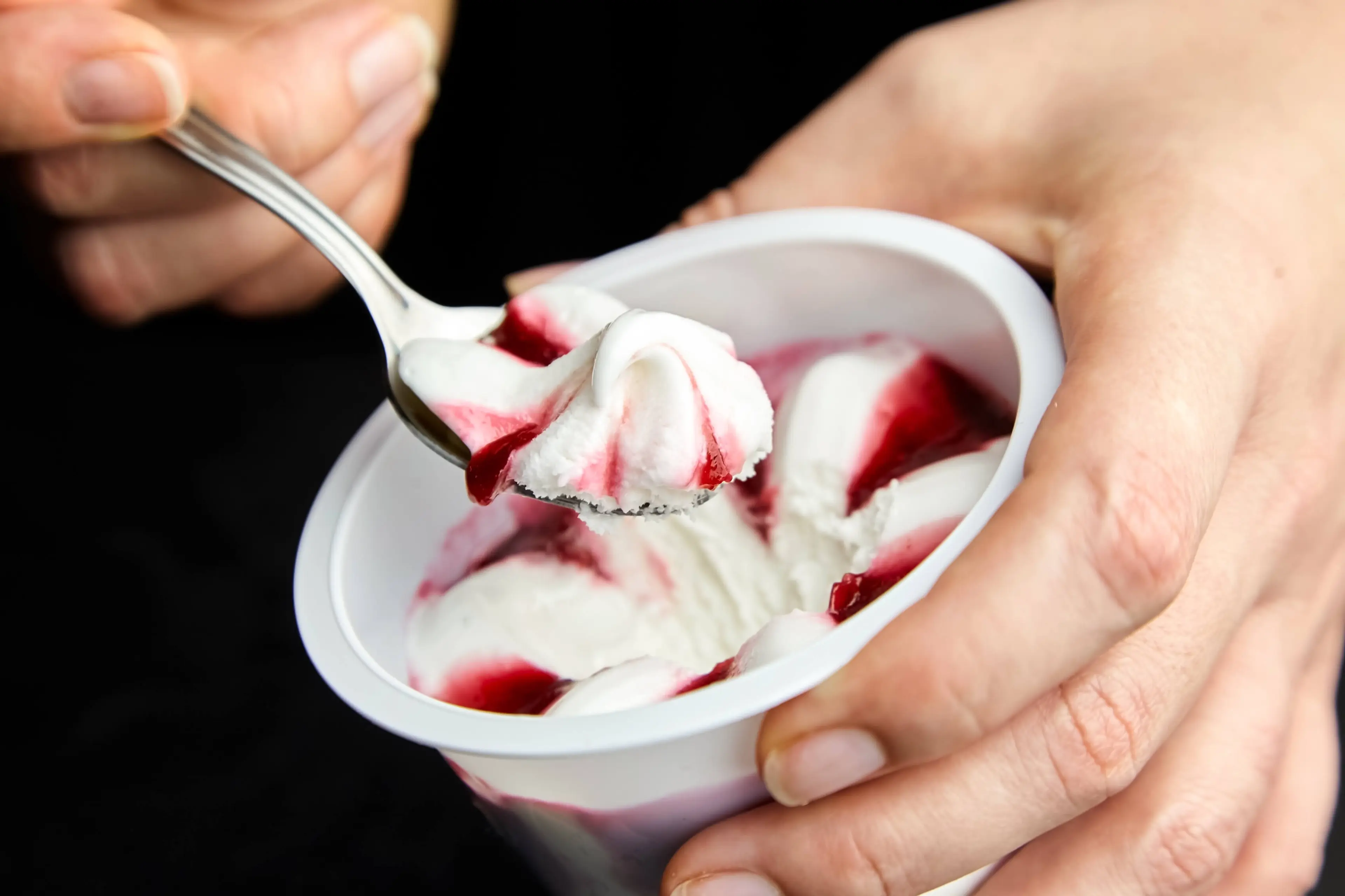 Yogurt ice cream in a white plastic cup on black background